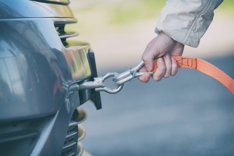 woman assembling towing line to a broken car
